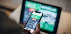 Foto di un uomo che utilizza l'applicazione mobile per le scommesse live