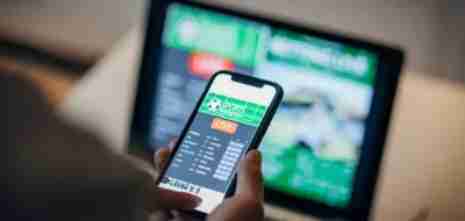 Foto di un uomo che utilizza l'applicazione mobile per le scommesse live